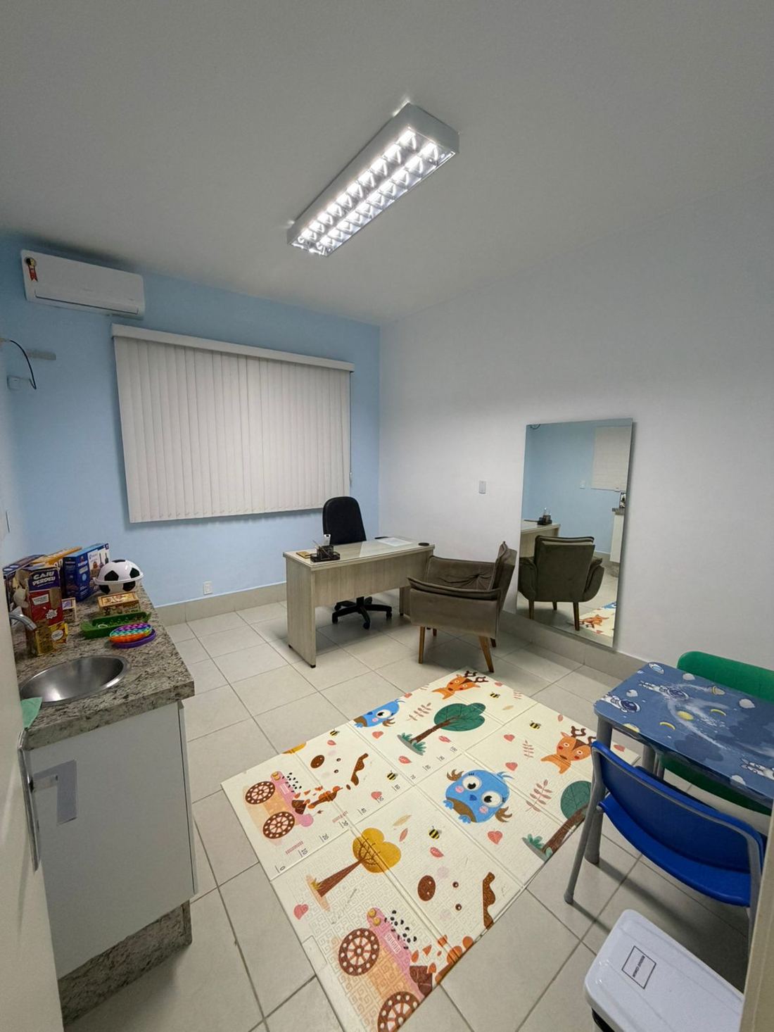 Sala de atendimento infantil com tapete e brinquedos